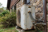 vieille pompe à chaleur contre une maison en pierre